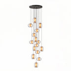 The largest cluster of clear glass Clérachic pendants, many at staggered heights from a wide round black canopy, on a white backdrop.