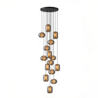 The largest cluster of smoke grey glass Clérachic pendants, many at staggered heights from a wide round black canopy, on a white backdrop.