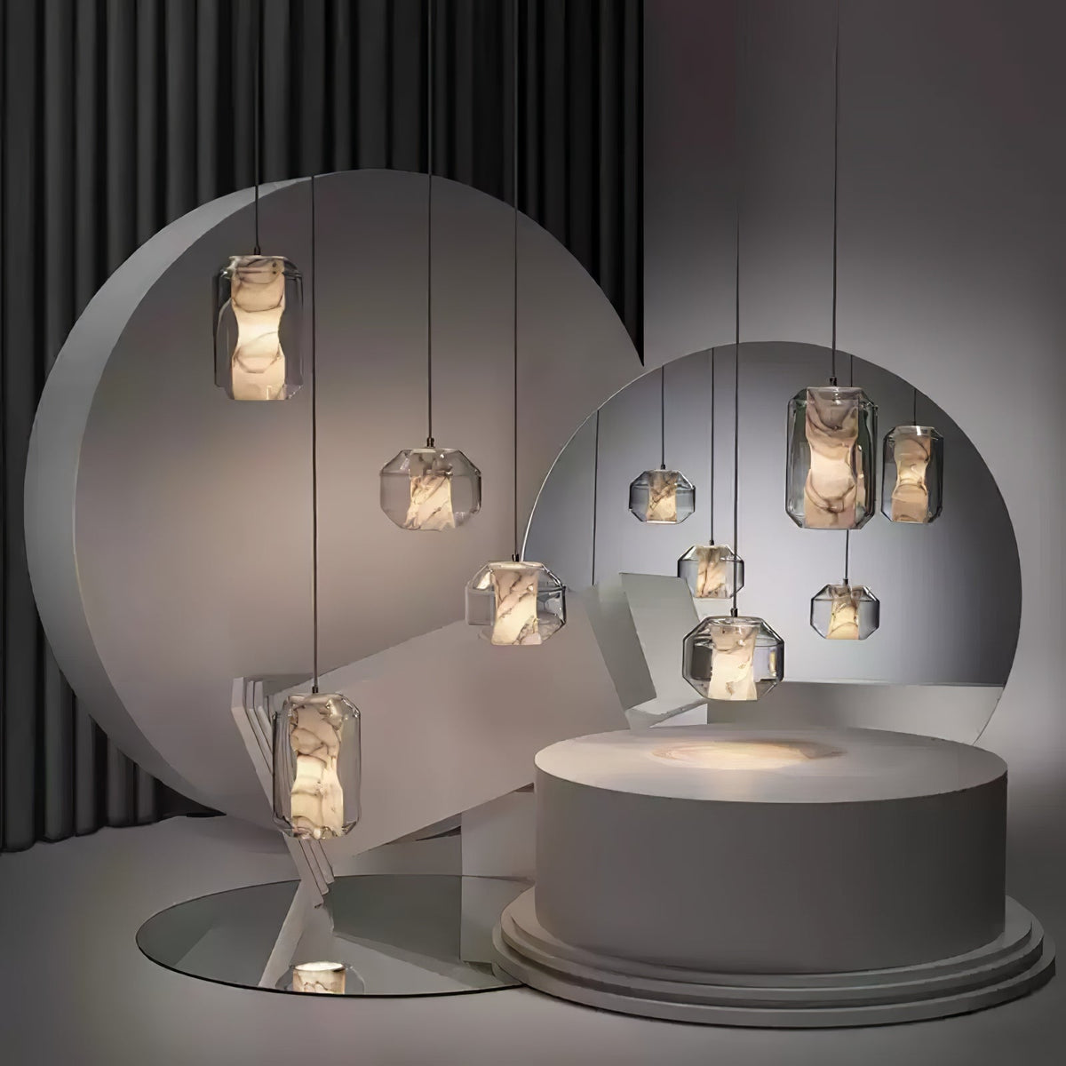 A group of Clérachic alabaster pendants in several sizes hangs in a dark studio set of round grey discs, a mirror and a pale plinth.