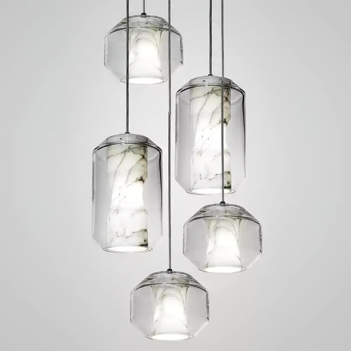 Five Clérachic pendants at staggered heights on a pale grey backdrop, cylinder and rounded-faceted glass shells each holding a veined alabaster core.