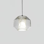 Front view of a wide, rounded-faceted Clérachic pendant on a pale grey backdrop, clear glass around a softly lit white alabaster core.