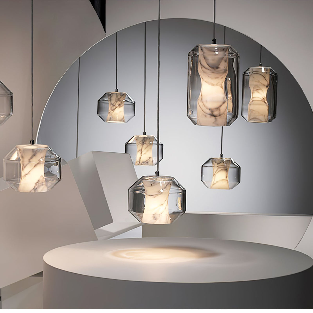 Clérachic alabaster pendants of several shapes hang before a round mirror in a pale studio set, with a circular plinth lit warm below.