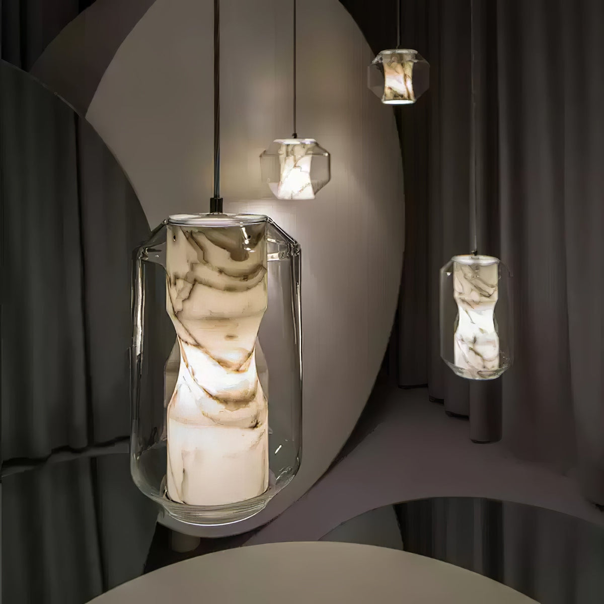 Close view of a tall clear glass Clérachic pendant with brown-veined alabaster glowing inside, in a curtained studio set with more pendants behind.