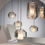 Rounded and tall Clérachic pendants hang at different heights in front of a mirror, their white alabaster cores veined in grey and brown.