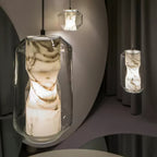 Close view of the waisted alabaster column glowing inside the clear glass shell of this Clérachic pendant, with a second pendant beyond.