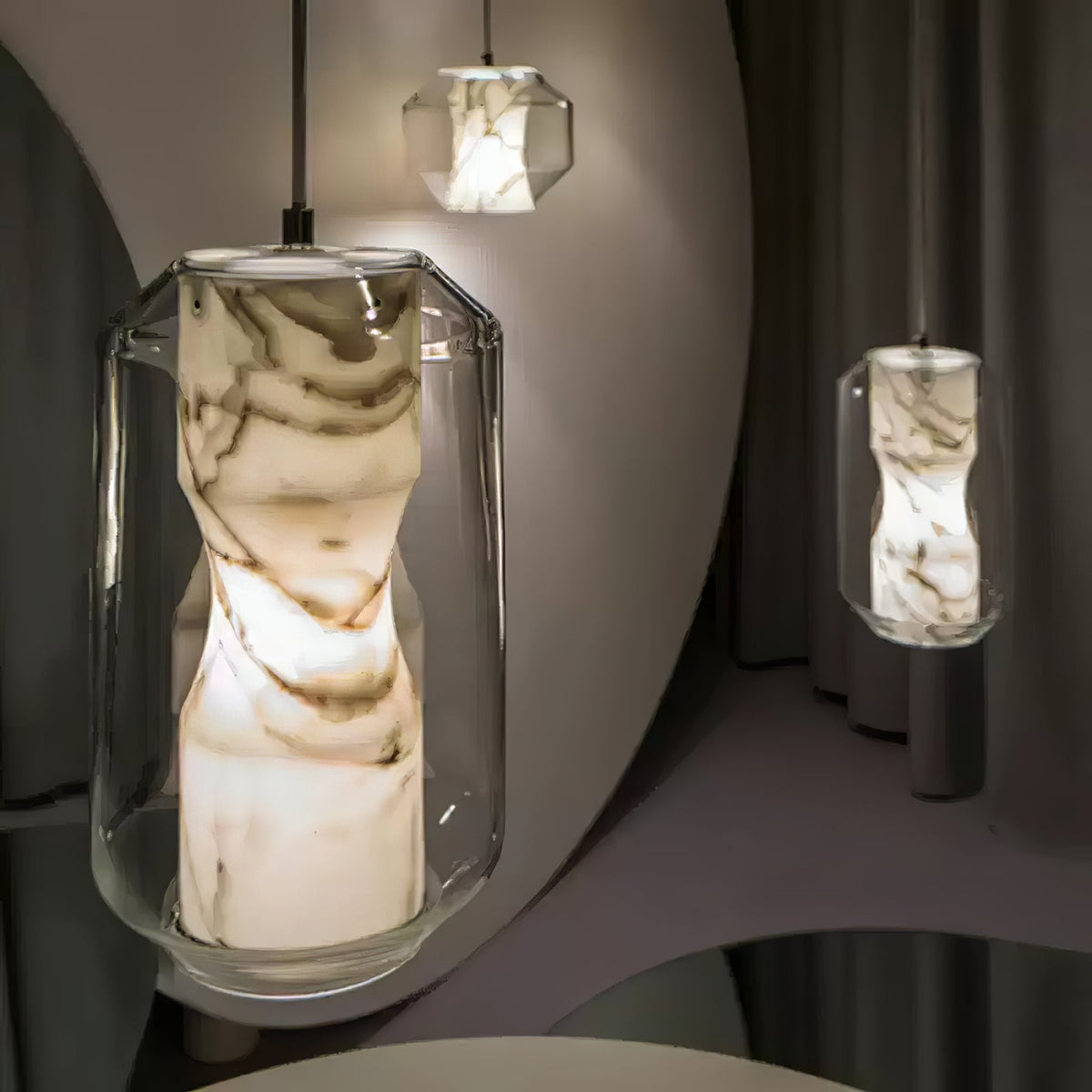 Close view of the waisted alabaster column glowing inside the clear glass shell of this Clérachic pendant, with a second pendant beyond.