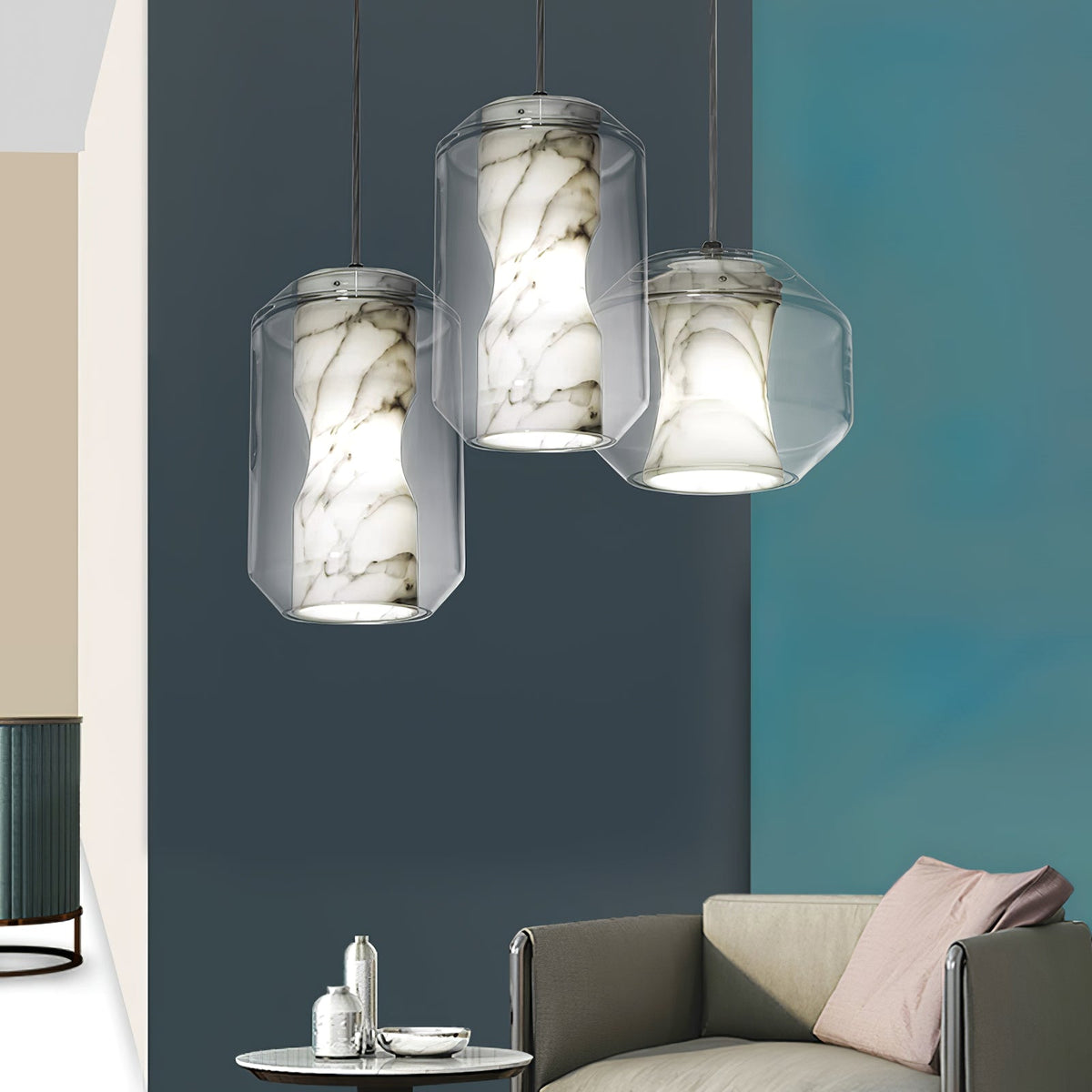 Three Clérachic pendants cluster in front of a deep teal wall above a grey sofa, each showing veined alabaster inside a clear glass shell.