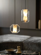 Closer view of a wide and a tall Clérachic pendant above a marble table with a shallow dish and a small vase, against dark wood panelling.