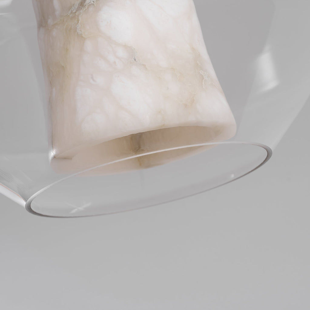 View from below of the alabaster column and the rim of the clear glass shell on this Clérachic pendant, on a pale grey backdrop.