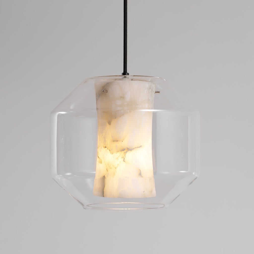 A wide Clérachic pendant on a black cord, its lit alabaster column veined in brown and cream inside a clear faceted glass shell.