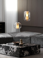 Two Clérachic pendants, one wide and one tall, hang at different heights above a black and white marble coffee table in a grey living room.