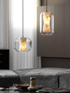 One wide and one tall Clérachic pendant glow beside sheer curtains and a wood-panelled wall, with a brown vase on the table below.