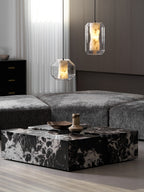 Wide view of two Clérachic pendants over a marble coffee table and grey sofa, with a dark cabinet with brass handles behind.