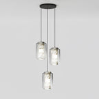 Three tall clear glass Clérachic pendants with veined alabaster hang at staggered heights from a round black canopy on pale grey.