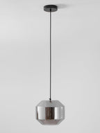A wide, unlit Clérachic pendant with a pale smoke grey glass shell hangs from a black cord and round canopy against a light wall.