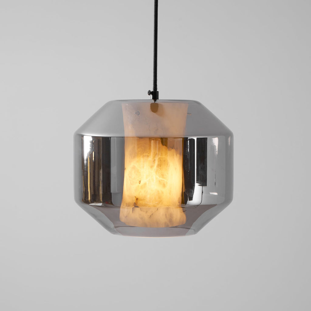 Close view of a wide smoke grey glass Clérachic pendant, the lit alabaster glowing amber behind the mirrored shell on a pale backdrop.