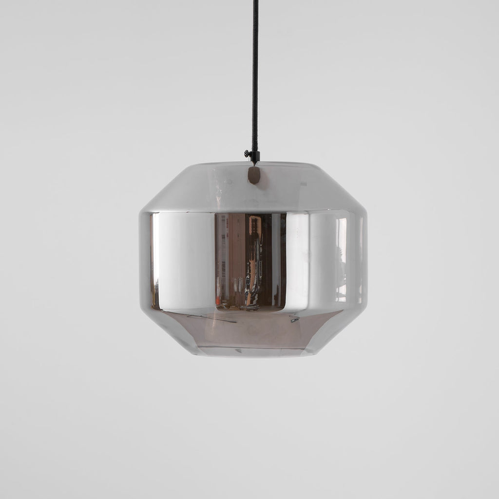 A wide, unlit Clérachic pendant with a pale smoke grey glass shell on a black cord, a small knot of the cord above, on light grey.