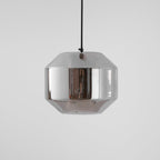 A wide, unlit Clérachic pendant with a pale smoke grey glass shell on a black cord, a small knot of the cord above, on light grey.