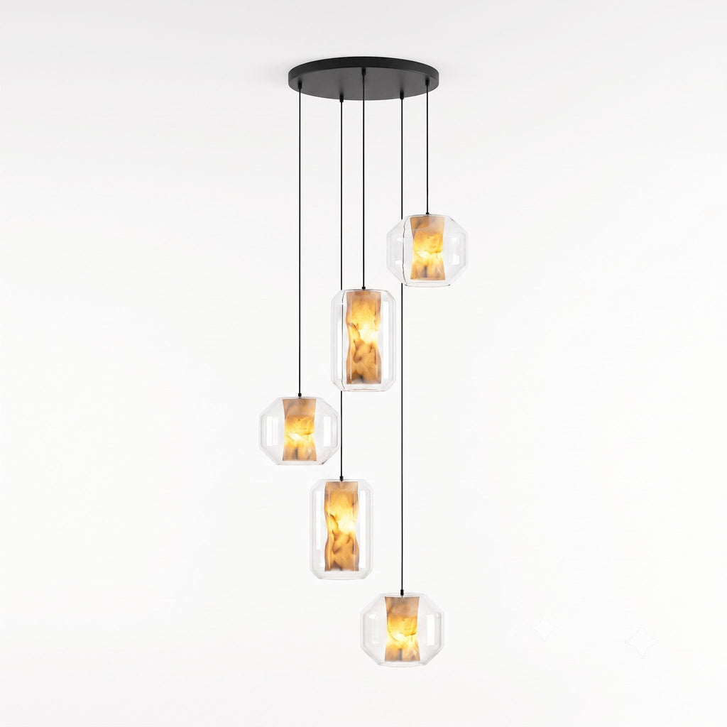 Five clear glass Clérachic pendants in wide and tall shapes hang at staggered heights from one round black canopy on a white backdrop, each lit amber.