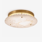 Clérachic alabaster disc ceiling light with a brass canopy and three small brass studs, seen from below on a plain white backdrop.