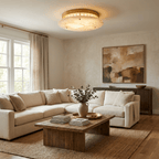This Clérachic alabaster ceiling light glows above a cream sectional sofa and a rustic wood coffee table in a bright living room.