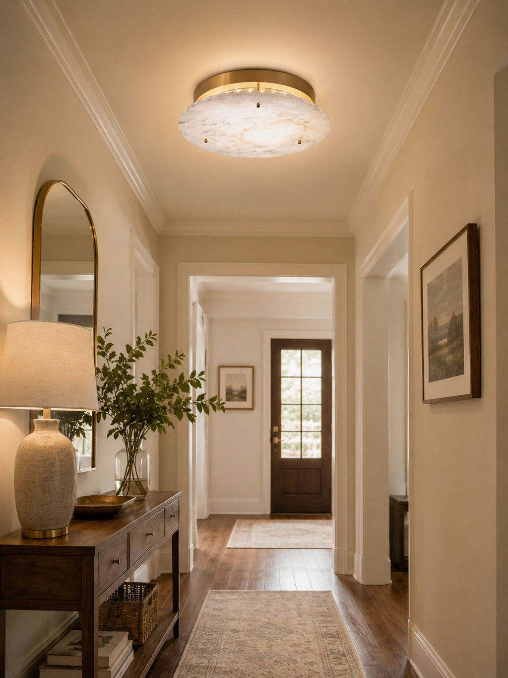 Clérachic brass and alabaster ceiling light in a hallway with an arched mirror, a wooden console and a front door at the end.
