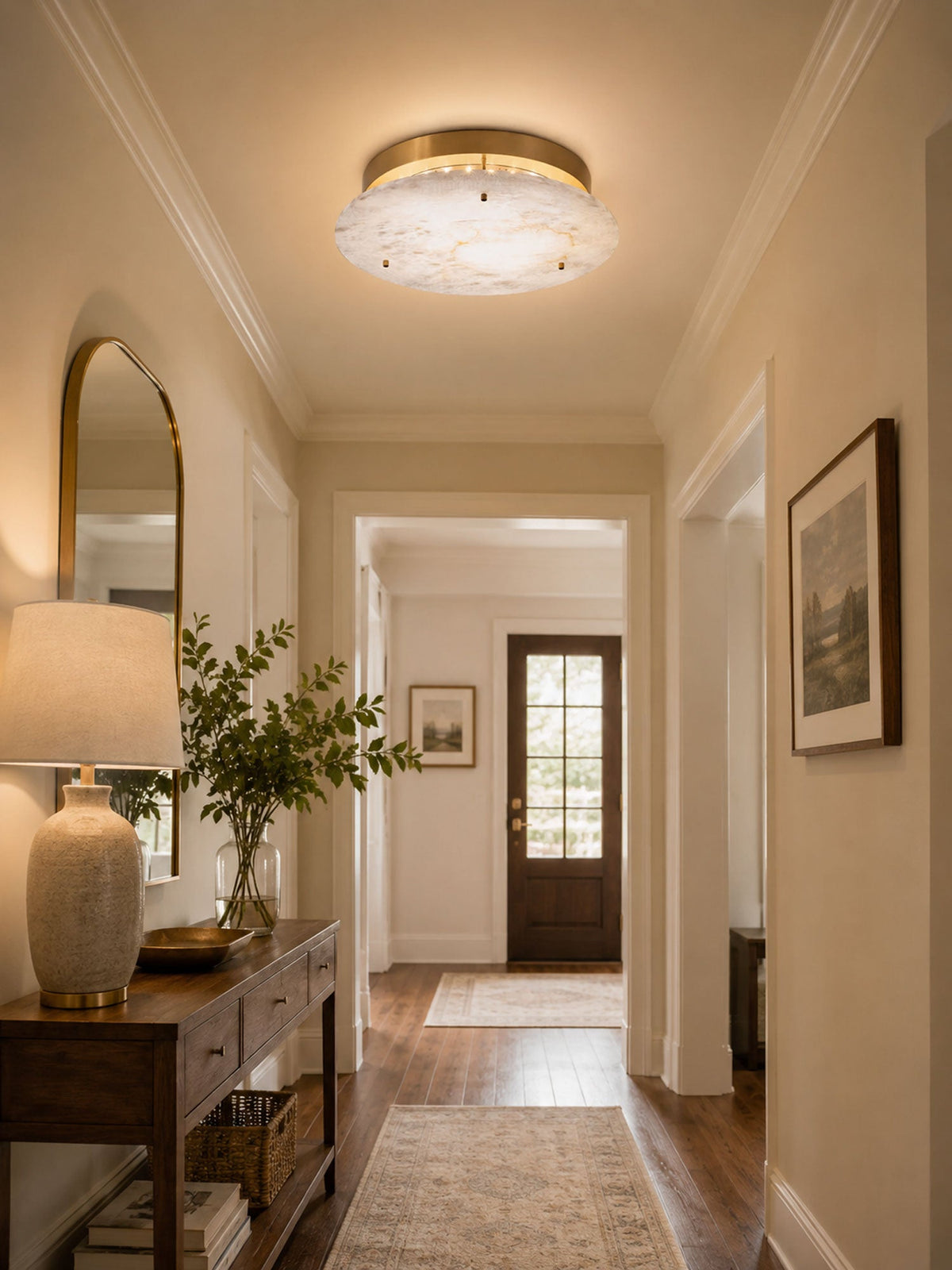 Clérachic brass and alabaster ceiling light in a hallway with an arched mirror, a wooden console and a front door at the end.