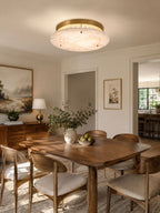 Clérachic flush-mount disc over a wooden dining table with cane-backed chairs, a bowl of green pears and a framed landscape.