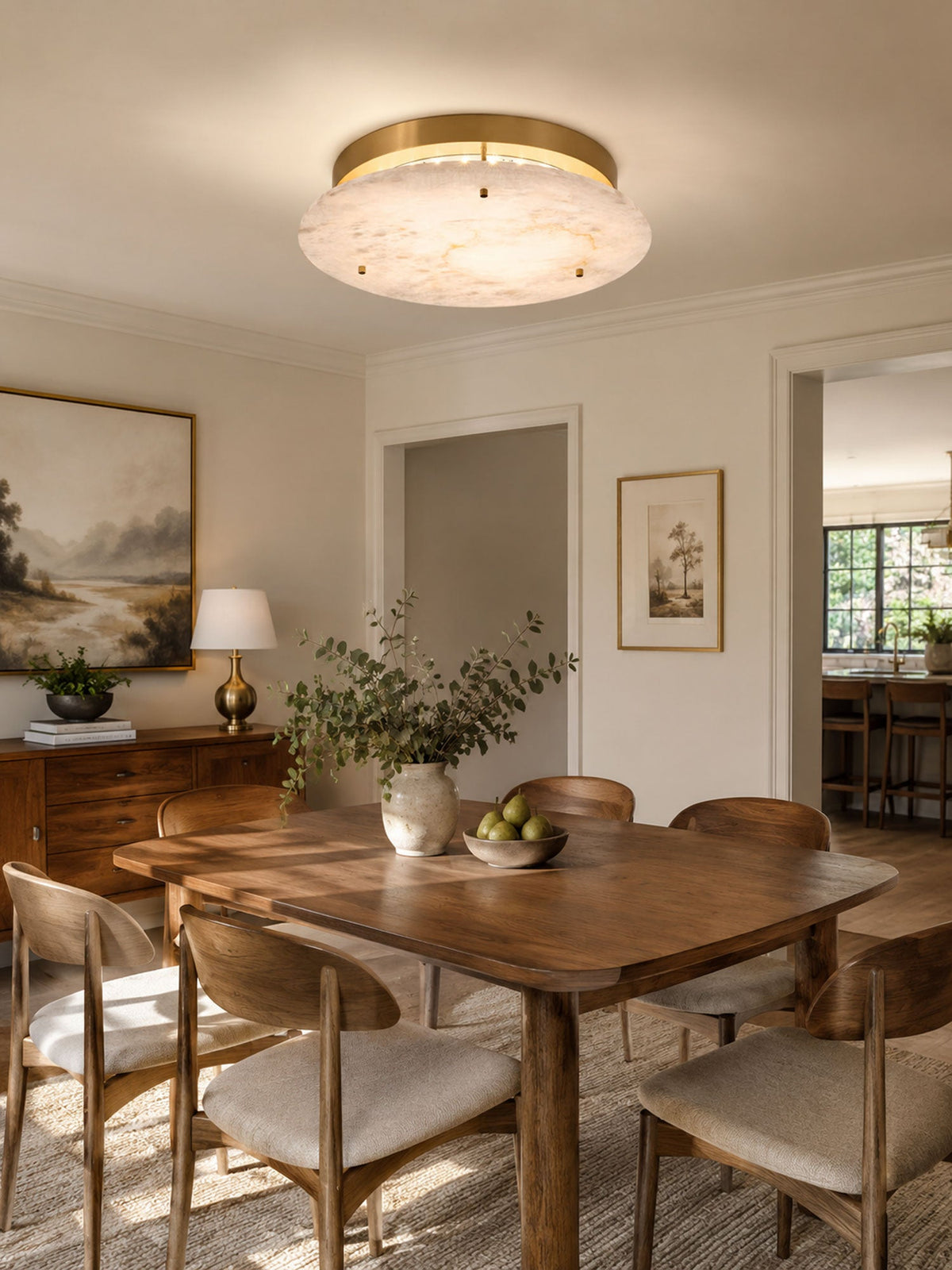 Clérachic flush-mount disc over a wooden dining table with cane-backed chairs, a bowl of green pears and a framed landscape.