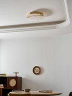 Clérachic alabaster ceiling disc seen from the side, switched off, beside a ceiling moulding and a dark wooden cabinet below.