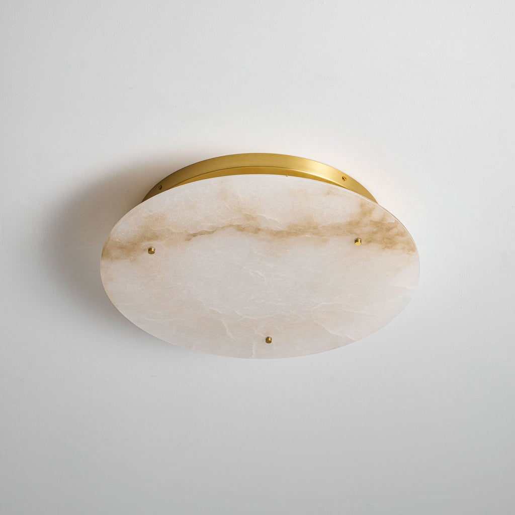 Clérachic alabaster disc mounted on a pale wall, shown from the front, with amber veining and a slim brass band behind.