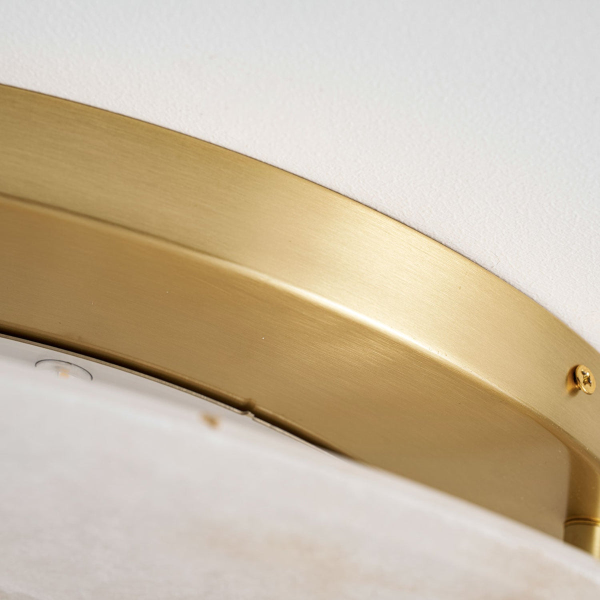 Close view of the brushed brass canopy ring and a fixing screw on this Clérachic ceiling light.