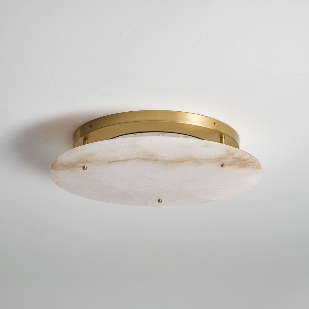 Clérachic flush-mount alabaster disc with a brass canopy, unlit, mounted on a pale grey ceiling and seen from one side.