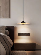 Clérachic Alabaster Disc Pendant Light over a dark oak nightstand, throwing a soft arc of light beside a leather bed.