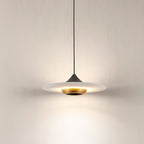 Close view of the Clérachic Alabaster Disc Pendant Light lit, warm light washing out from under the stone onto the wall.