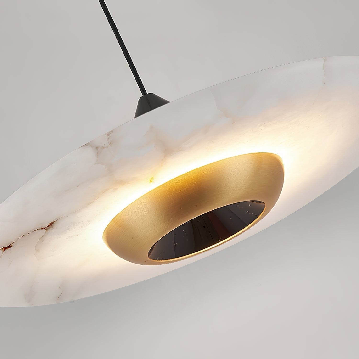 Underside detail of the Clérachic Alabaster Disc Pendant Light: brushed brass bowl ringed by rust-toned alabaster veining.