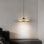 Clérachic Alabaster Disc Pendant Light above a dark wood console, a warm halo of light on the bedroom wall behind it.