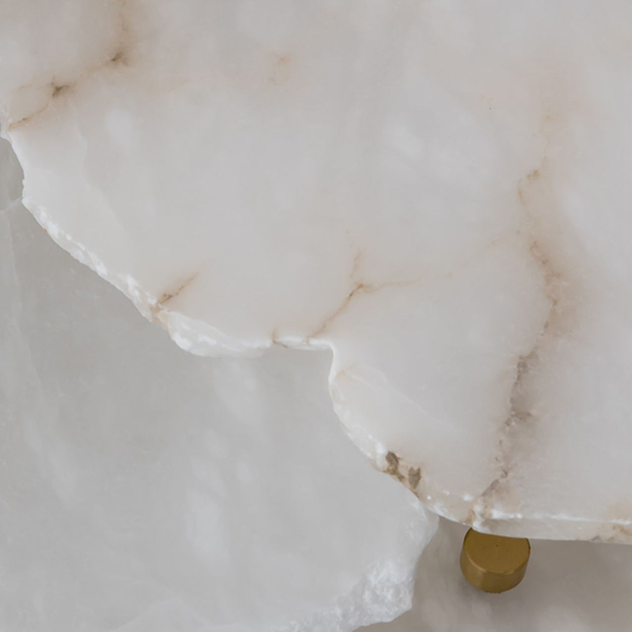 The natural stone of the Clérachic Alabaster Disc Pendant Light close up, raw quarried edge and honey-toned veining.