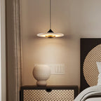 Clérachic Alabaster Disc Pendant Light lighting a cane-fronted bedside chest and ribbed ceramic vase in a warm bedroom.