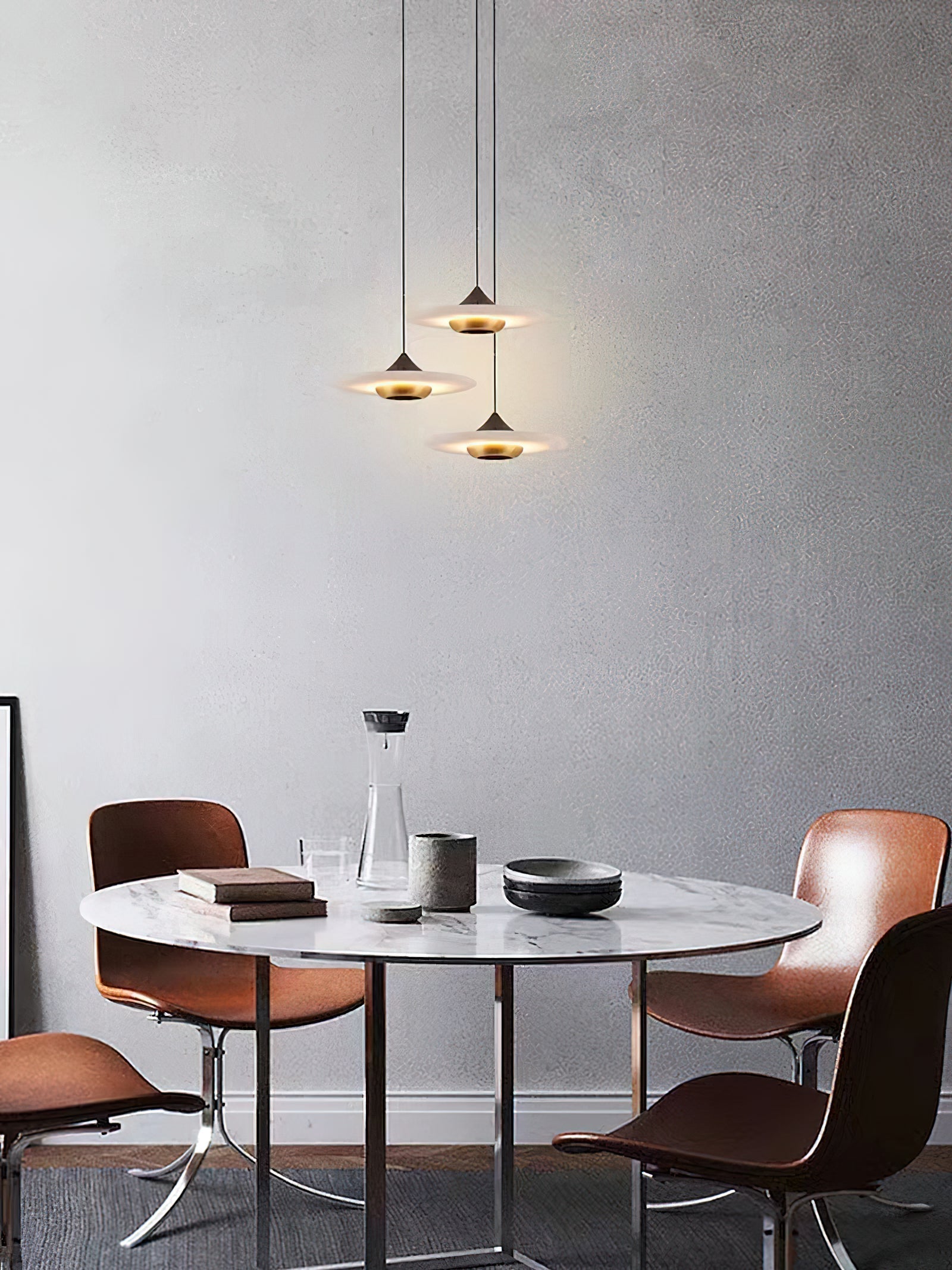 Three Clérachic Alabaster Disc Pendant Lights staggered at different drops over a round marble dining table.