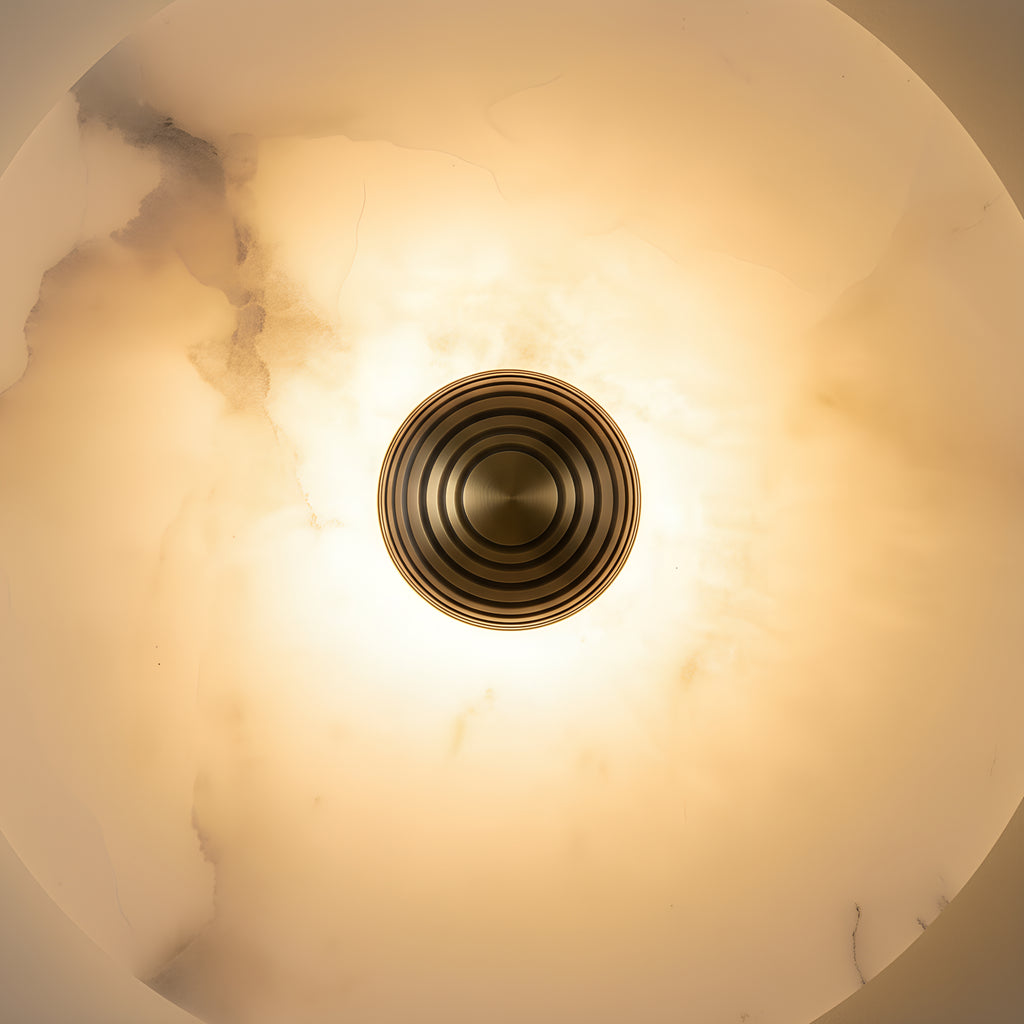 Close view of the turned brass boss set into the alabaster, the stone translucent enough to show its veins running through the light