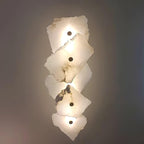 The Clérachic alabaster lamp in its five-head zigzag arrangement, each stone shade glowing warmly on a plain wall.
