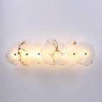 Clérachic's seven-head alabaster lamp spans a white wall, each stone shade lit from within.