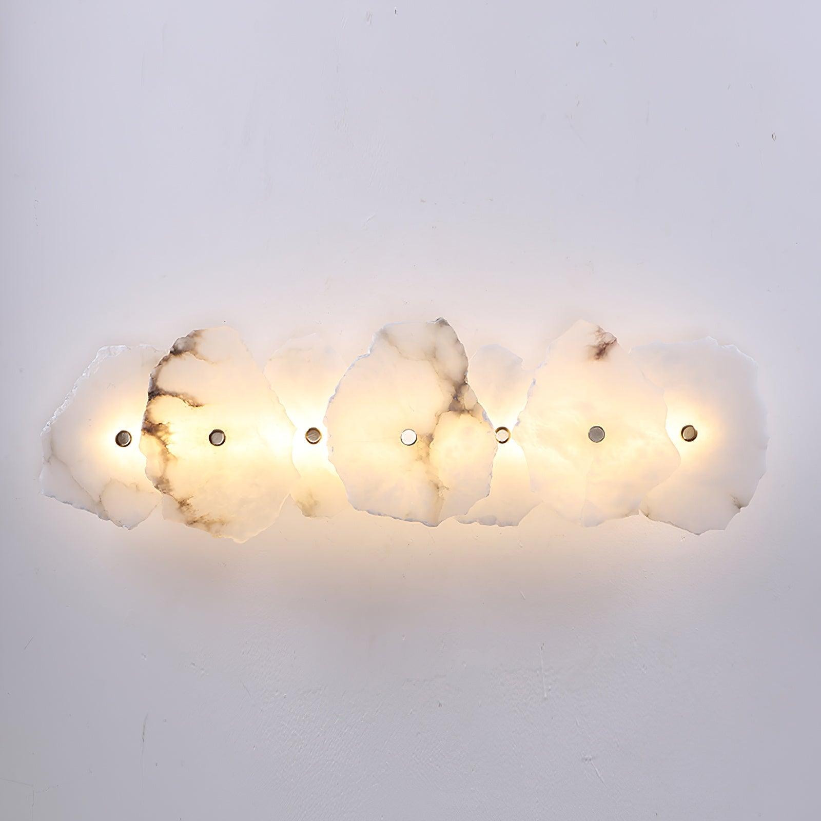 Clérachic's seven-head alabaster lamp spans a white wall, each stone shade lit from within.