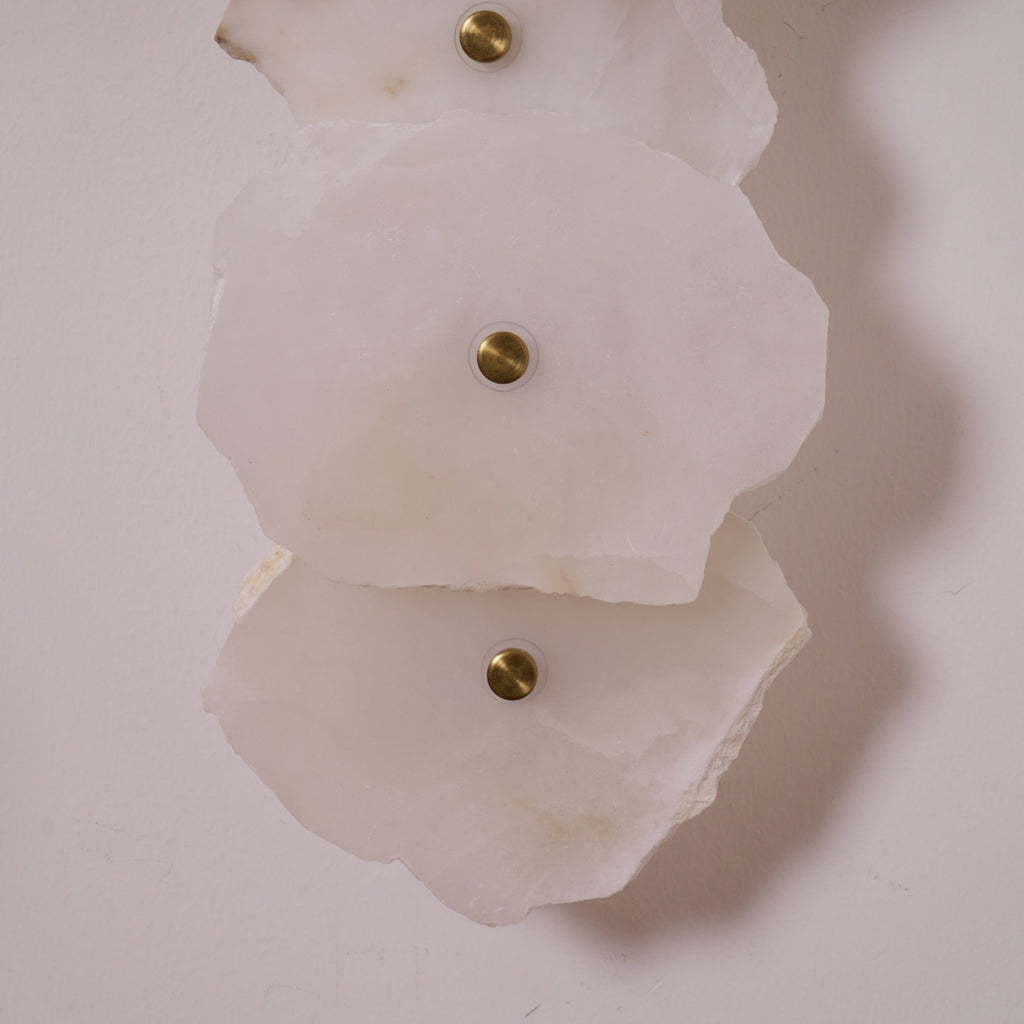 Clérachic's alabaster shades in close-up, unlit, revealing the brushed brass mounting caps at each centre.