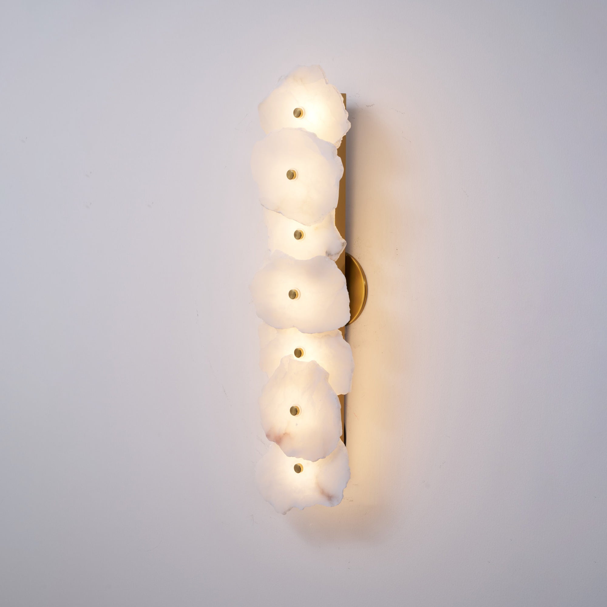 The Clérachic six-head alabaster lamp lit more brightly, its stone shades glowing warm along the wall.