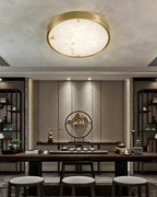 Round Clérachic alabaster flush ceiling light in a tea room, centred on the ceiling above a long dark table and stools.