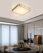 Square Clérachic alabaster flush ceiling light above a round marble dining table, with the kitchen visible beyond.