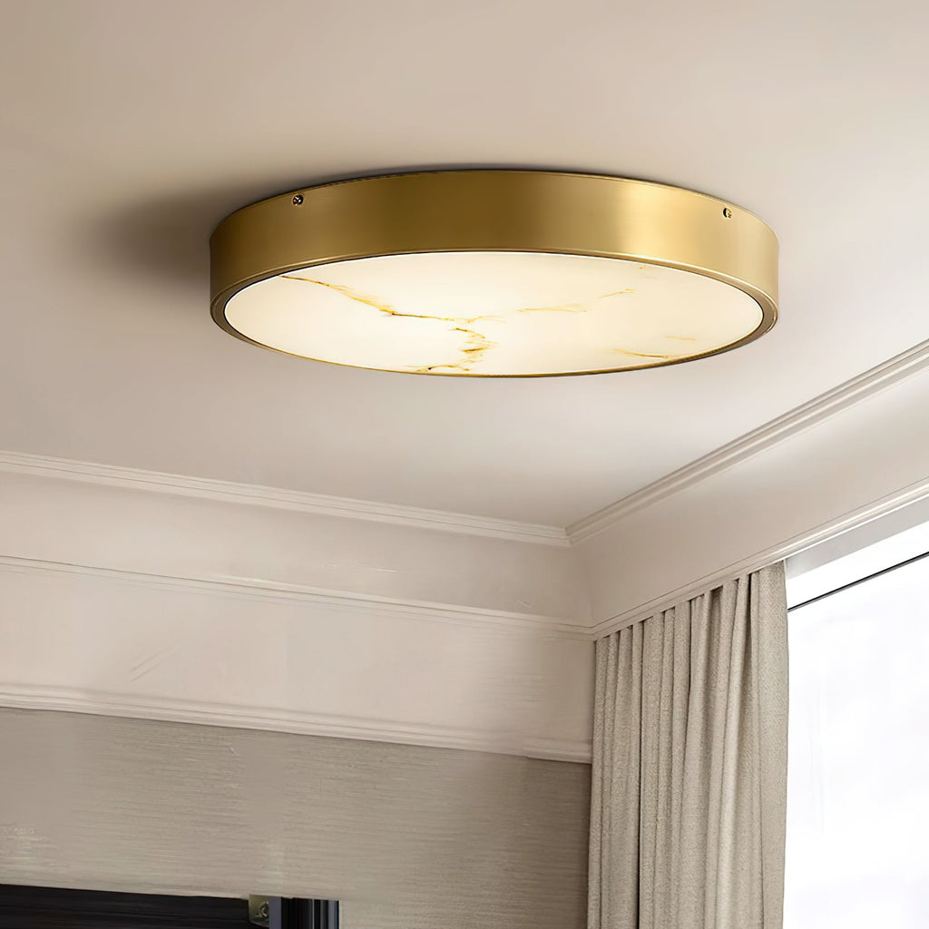 Round Clérachic alabaster flush ceiling light seen close on a ceiling with crown moulding, the brass band a warm, deep rim.