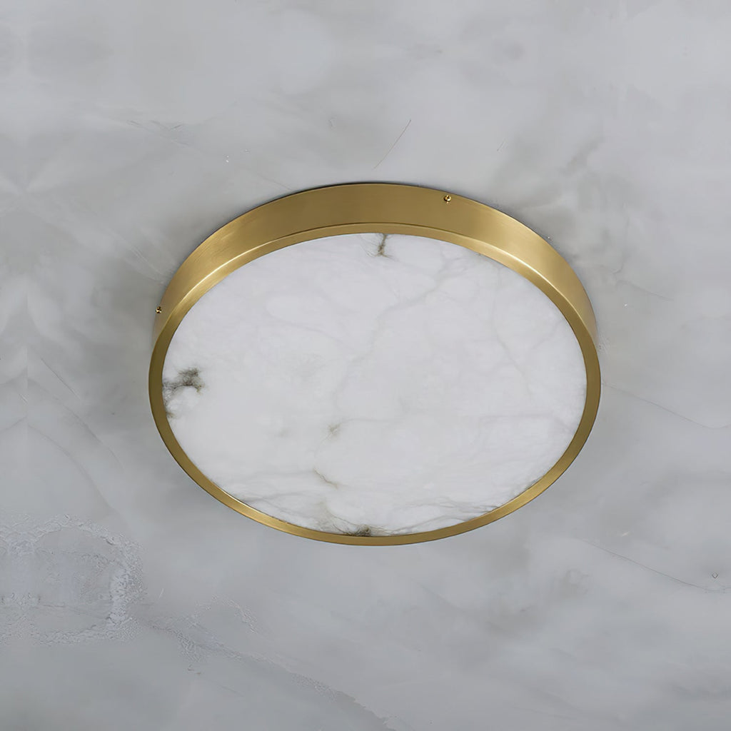 Round Clérachic alabaster flush ceiling light viewed straight up on a marble ceiling, brass band circling the stone face.